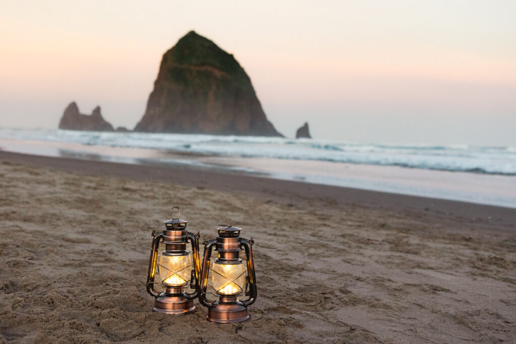 lanterns on beach with Haystack rock behind couple.