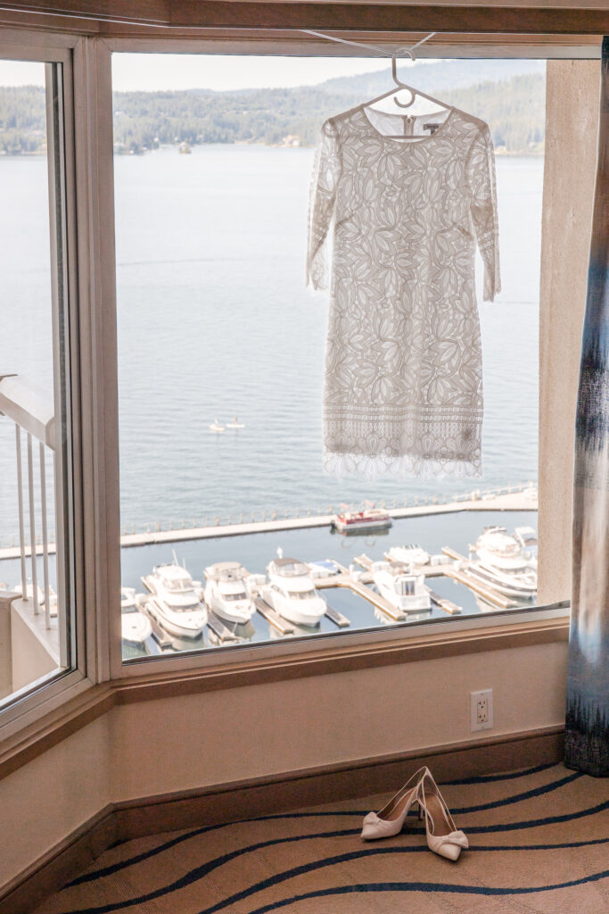 Wedding dress hanging in the window of Coeur d'Alene suite with boats out the window.