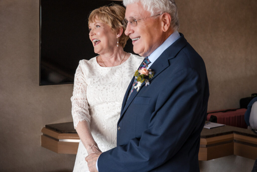 Bride laughing joyfully while holding groom's hand after ceremony