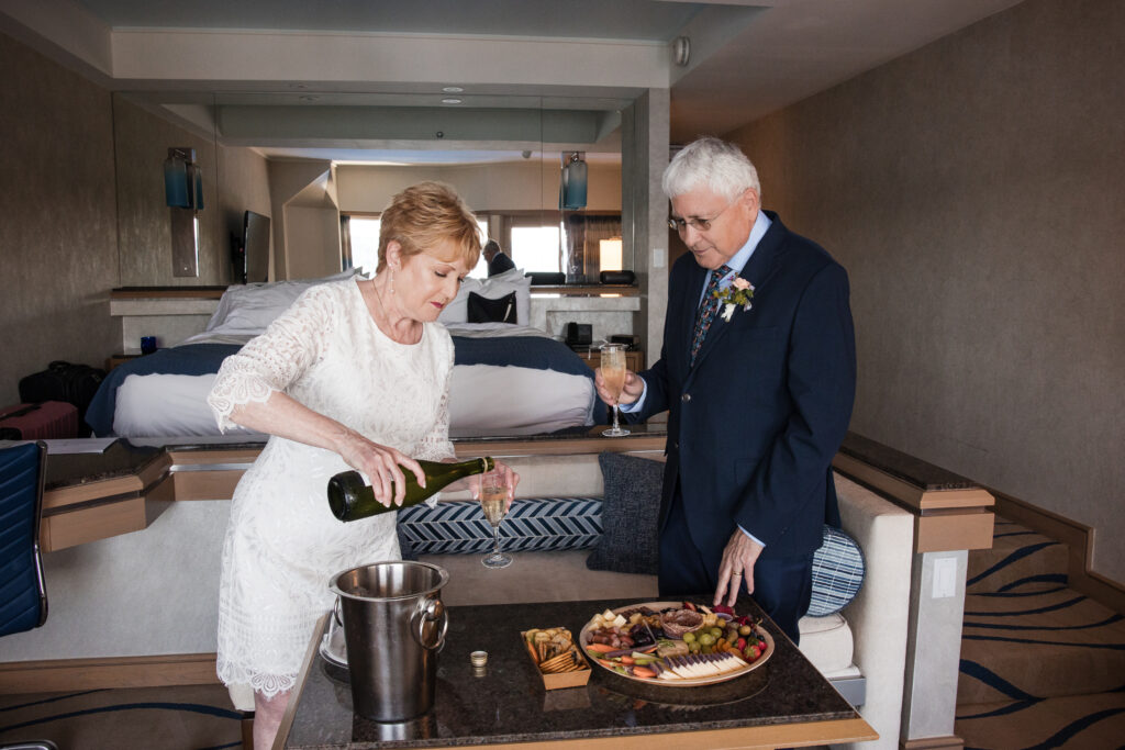 Bride pouring sparkling wine while the groom raises a glass for a toast.