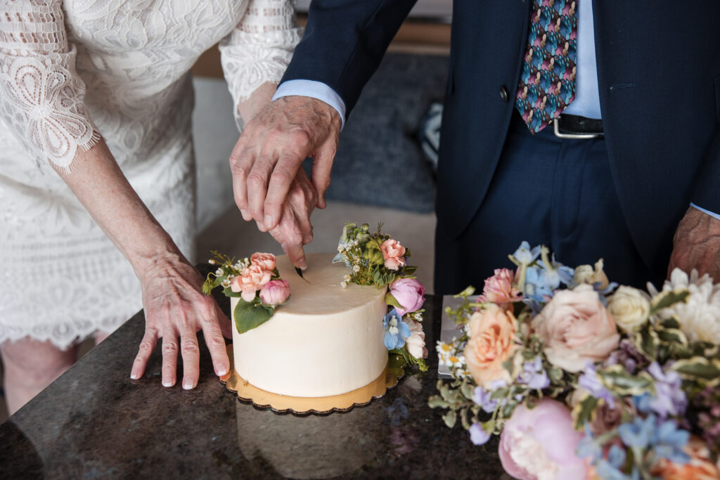 Close-up of an older couple cutting their wedding cake together during an intimate elopement in Coeur d’Alene, Idaho.