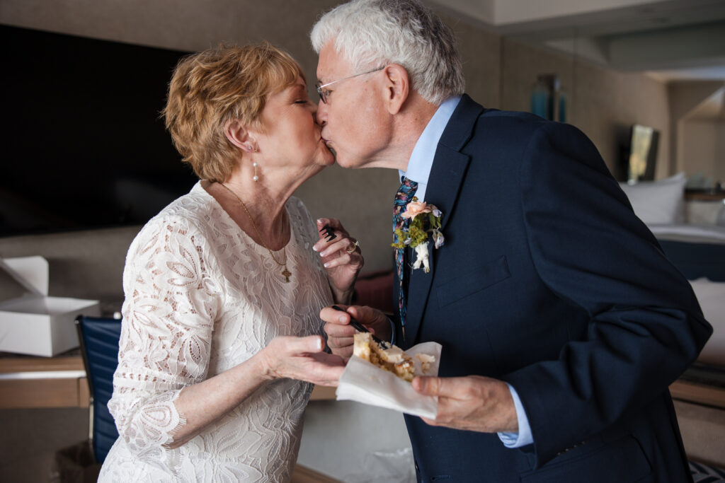 Mature couple shares a joyful kiss after enjoying cake at their private Coeur d’Alene elopement.