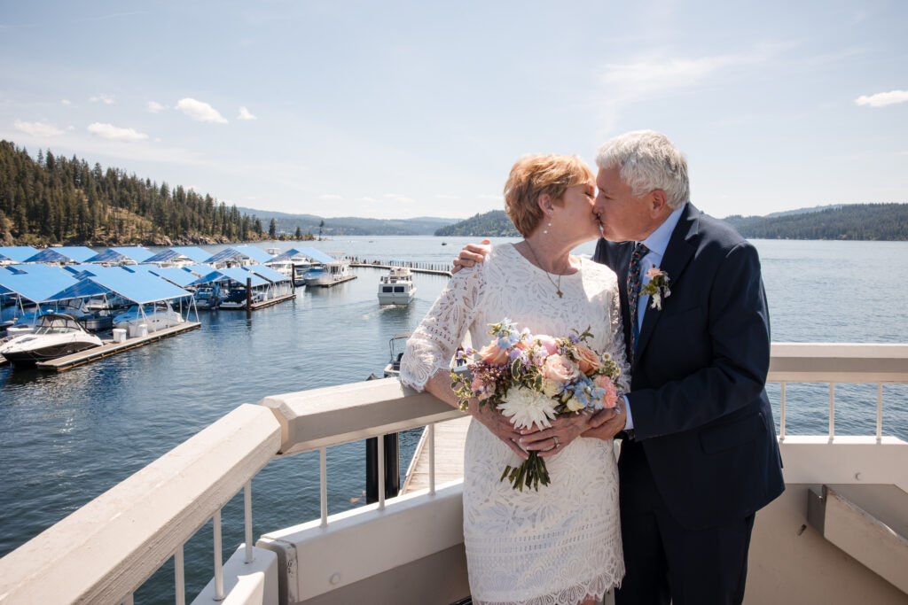 Happy bride and groom on a dock with Lake Coeur d’Alene in the background during a spring elopement.