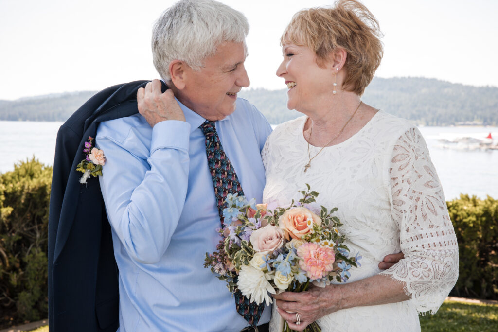 Couple smiling at each other holding bouquet – lakeside elopement Coeur d’Alene