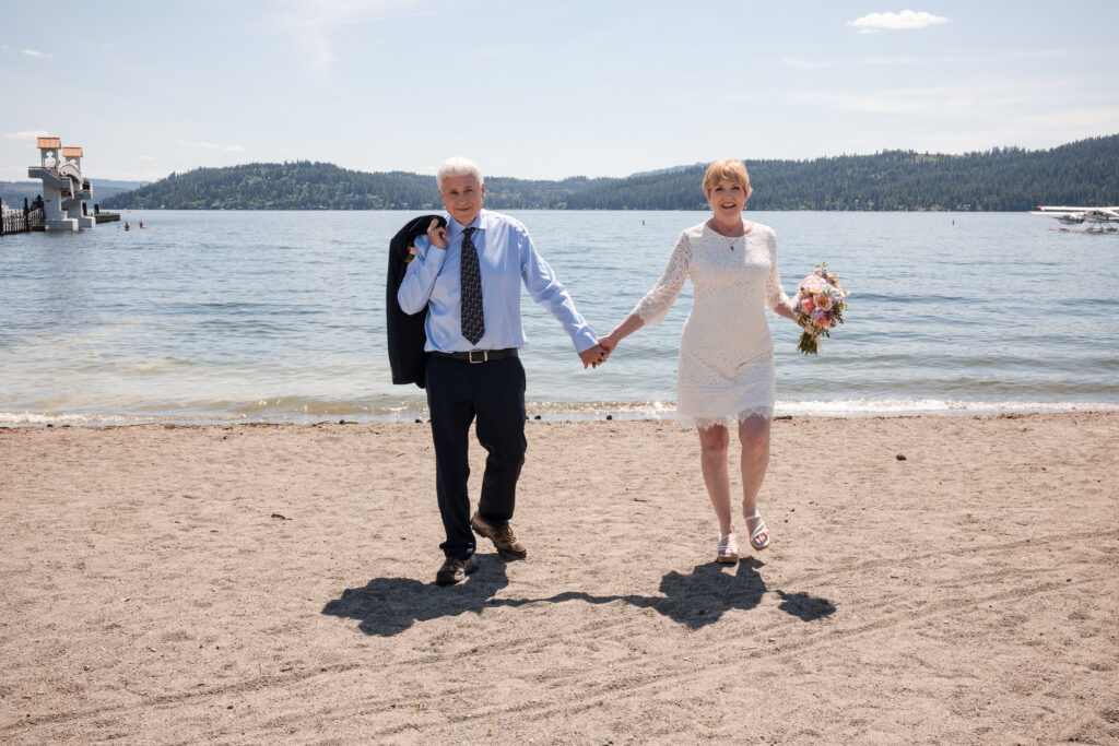 Newlywed couple walking hand in hand on beach after Coeur d’Alene elopement