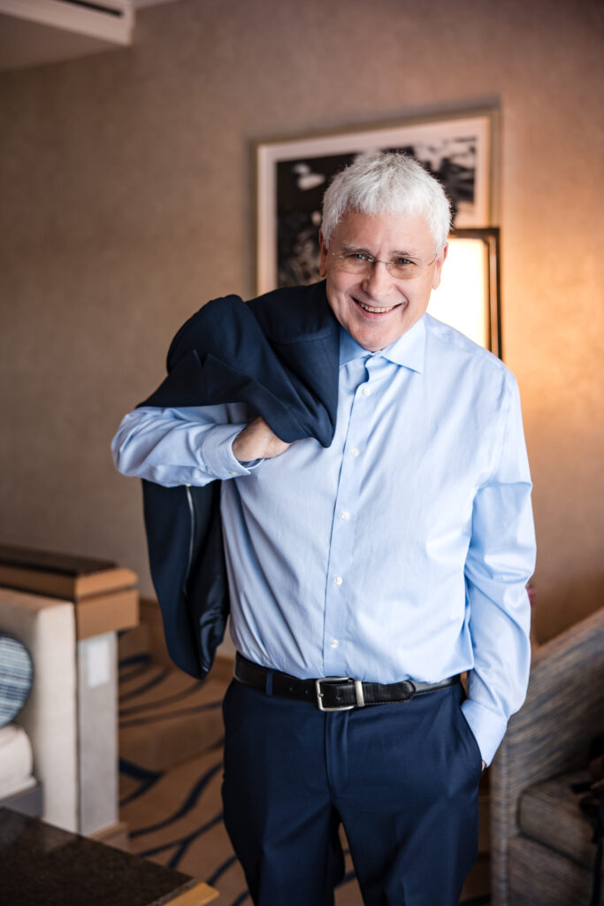 Groom grinning as he poses with suit jacket over shoulder before elopement