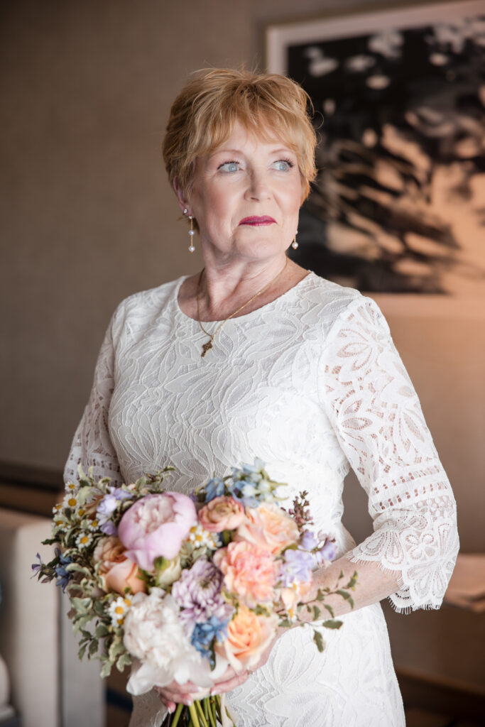 Bride holding bouquet, looking off camera in lace dress before elopement
