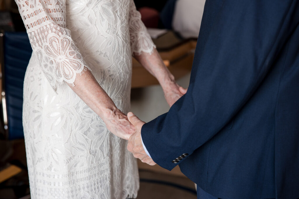 Close-up of couple holding hands during intimate indoor ceremony