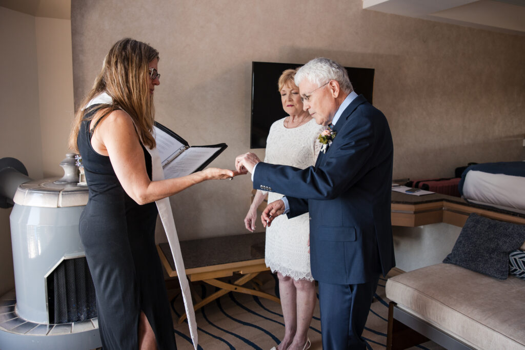 Couple reaching for rings from officiant