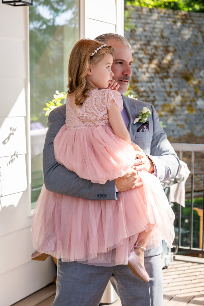 Groom dancing on the deck holding his daughter in her pink dress