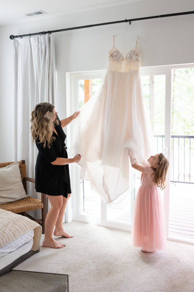 bride and daughter looking up at wedding dress hanging in the window.
