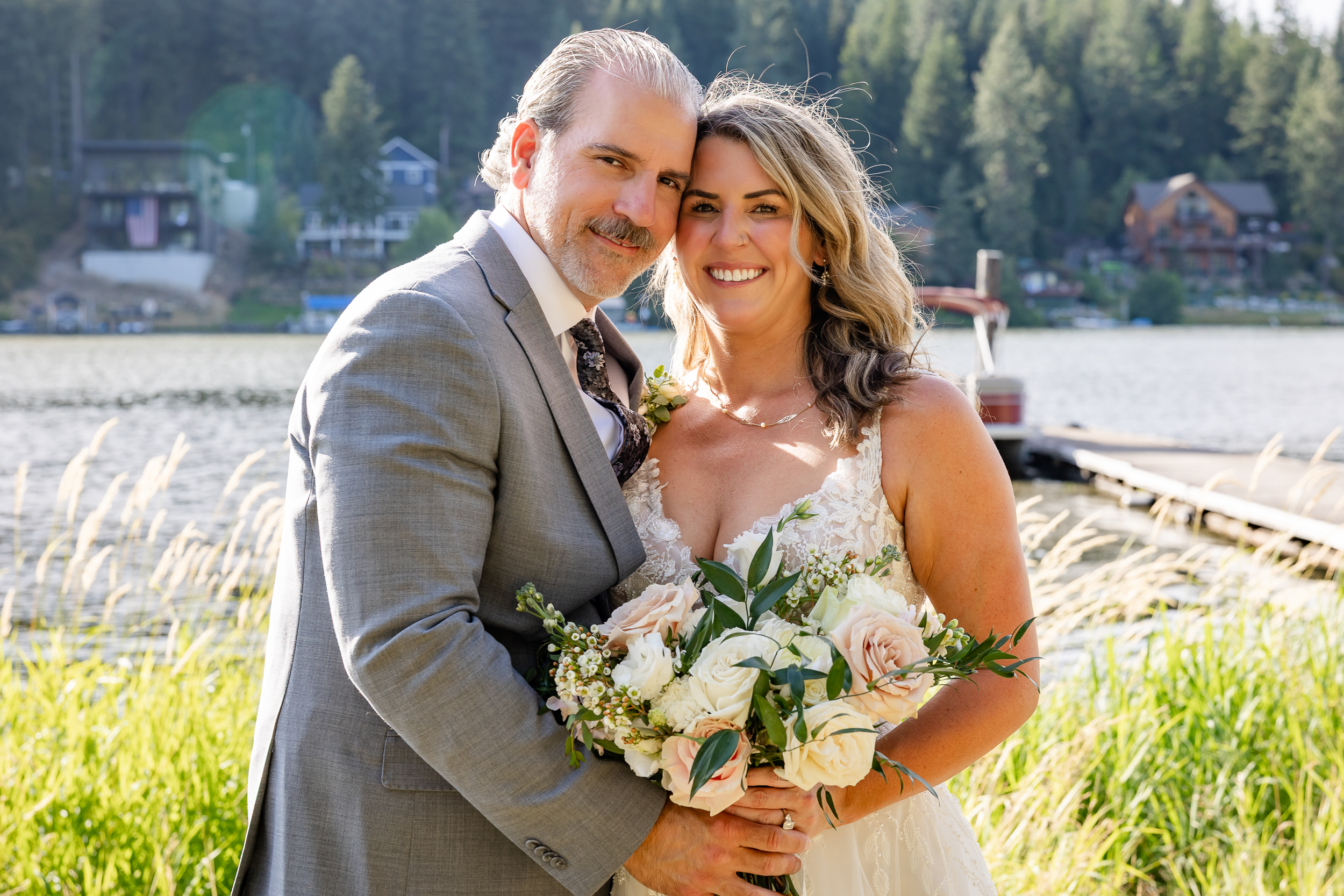 Bride and Groom holding each other and bouquet in front of lake