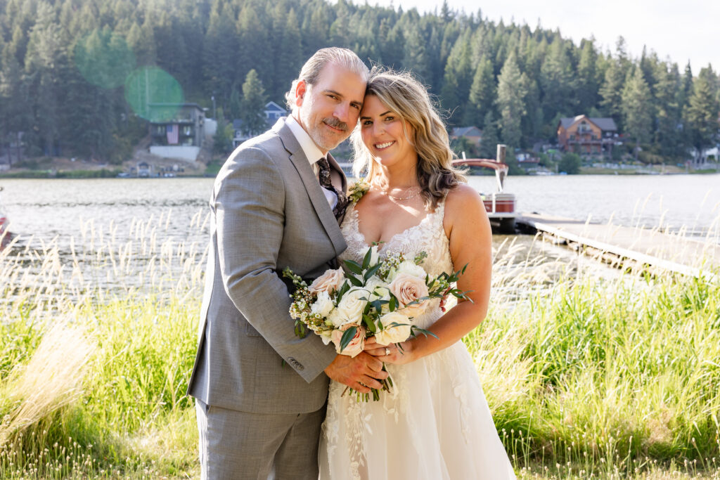 Bride and groom portrait by the lake with the sun shining down.
