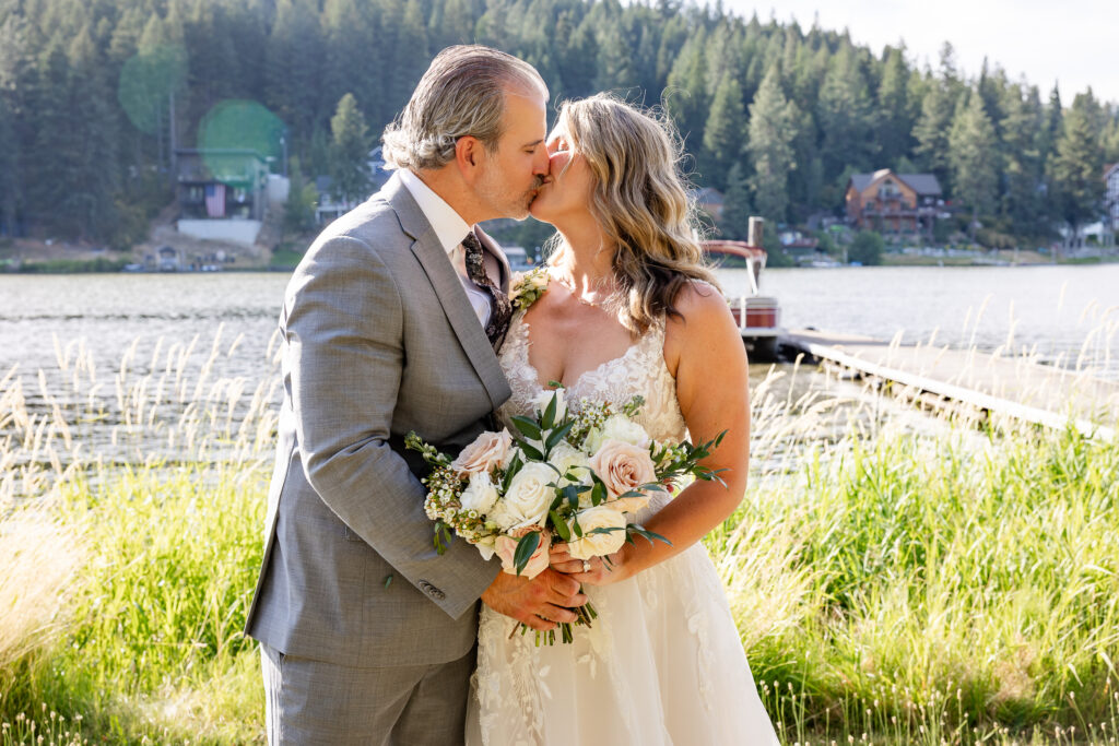 Bride and groom portrait by the lake kissing