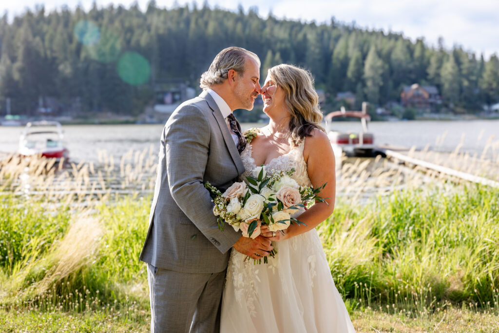 Bride and groom portrait by the lake kissing