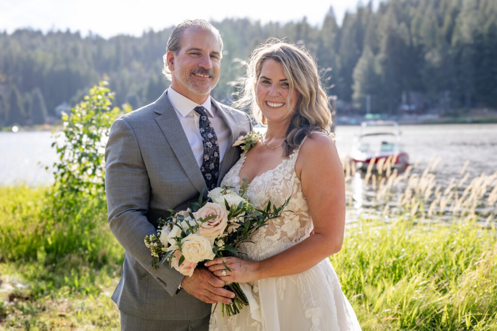 Bride and groom portrait by the lake with the sun shining down.