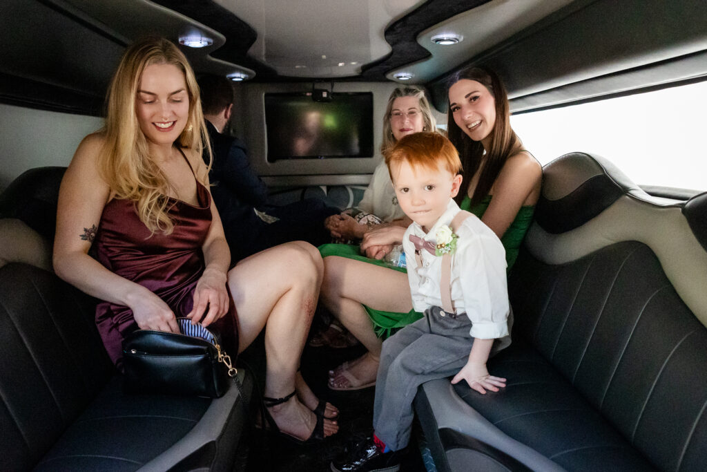 children, and guests sitting in a stretch limo after a lakeside wedding.