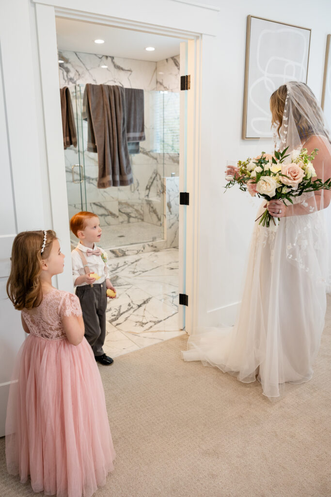 Son and daughter looking up at bride as she is ready for the ceremony with bouquet in hands