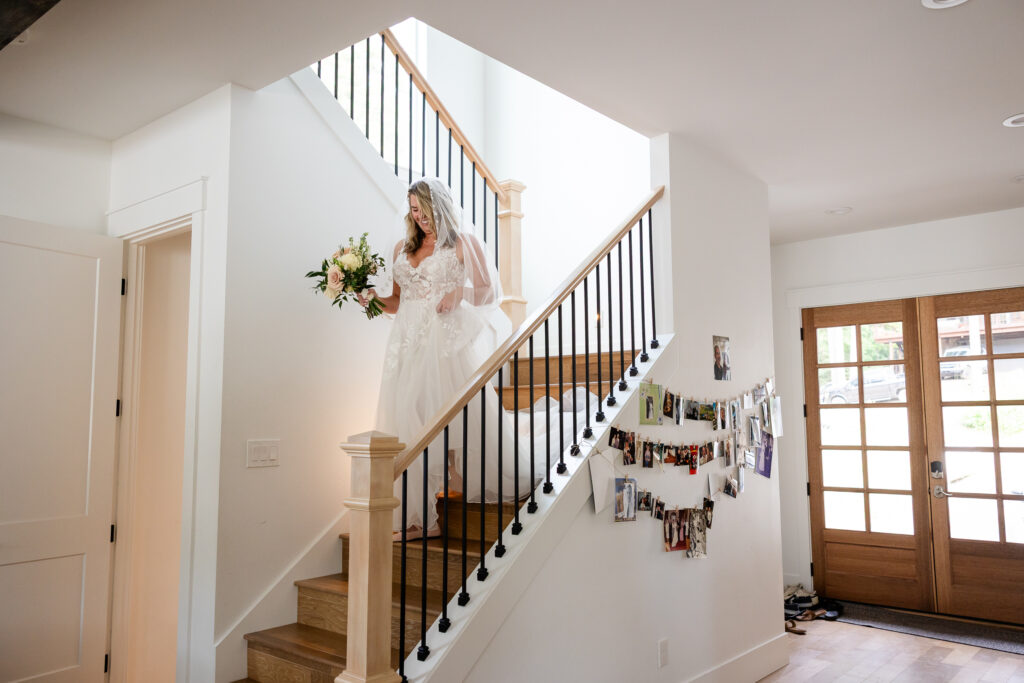 The bride walking down the wooden staircase toward her father before intimate Idaho wedding.