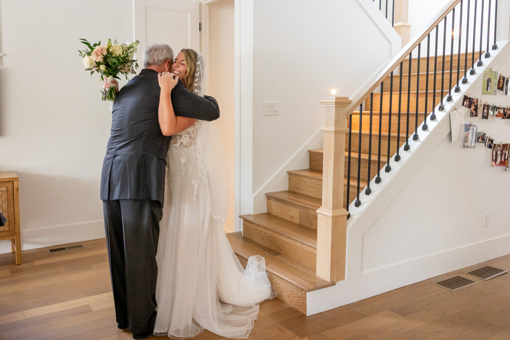Bride hugging her father at the bottom of the stairs before ceremony.