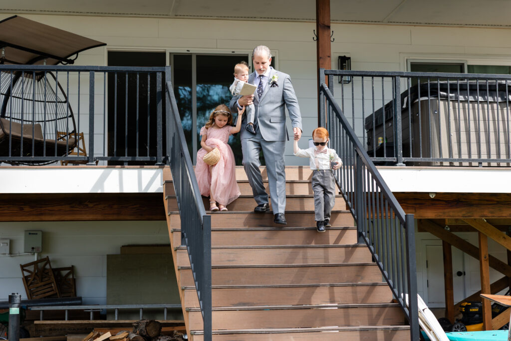 Groom comming down staricase towards ceremony with all three children