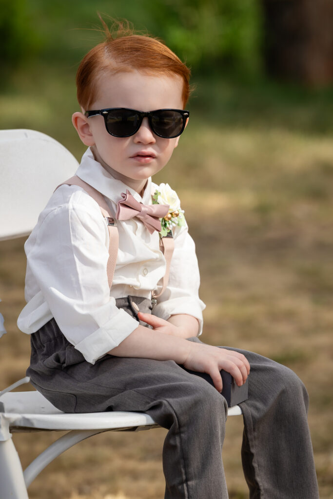 Young son looking towards ceremony wearing his sunglasses