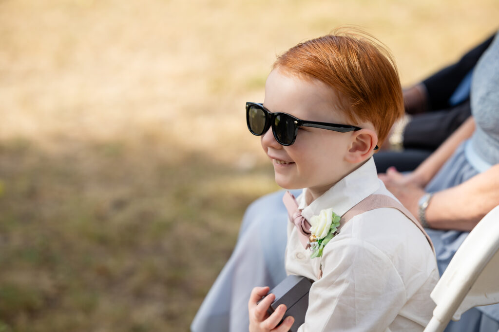 Son wearing sunglasses, dressed in a bow tie and suspenders smiling