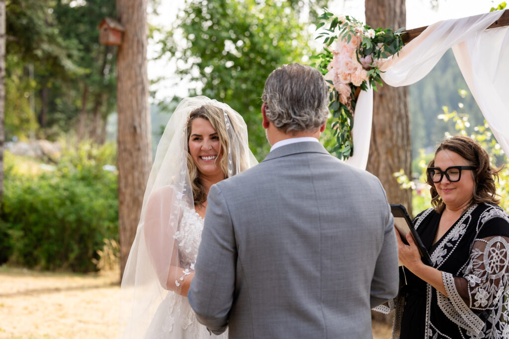 Bride smiling at guests while holding grooms hands.