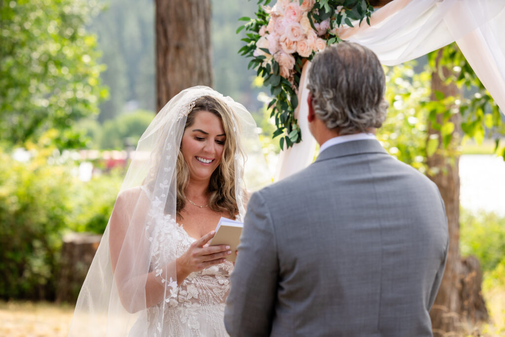 Bride smiling at groom while reading her vows.