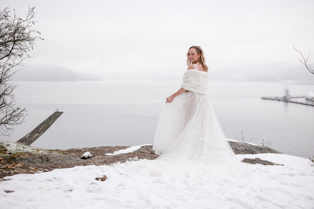 Bride facing over her shoulder in the snow with Lake Coeur d' Alene in the background