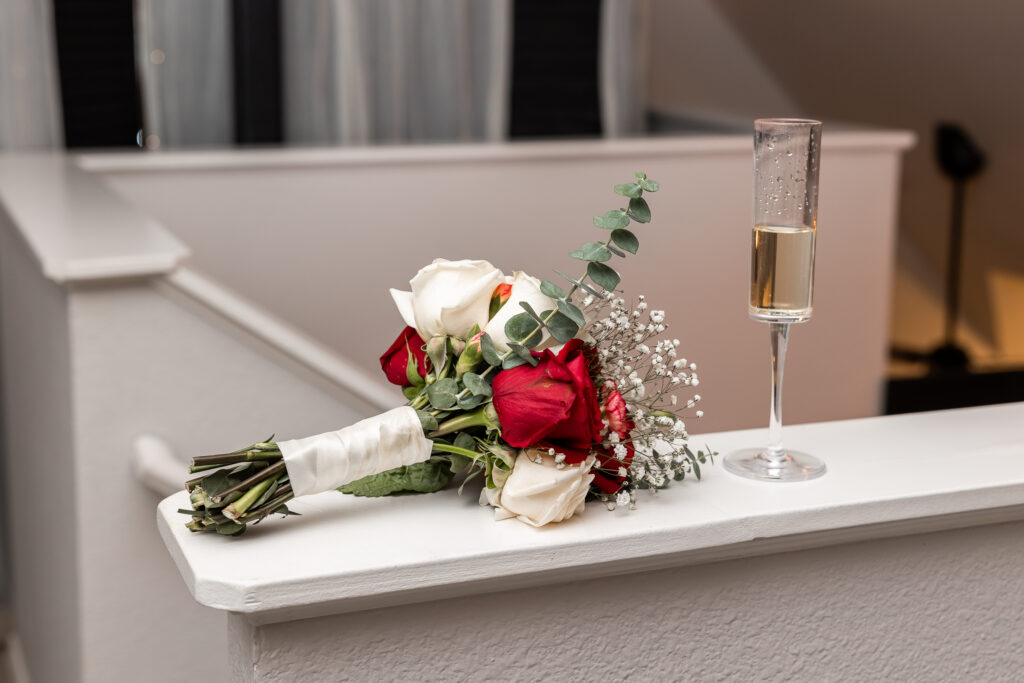 Bridal bouquet and glass of champagne on a white self